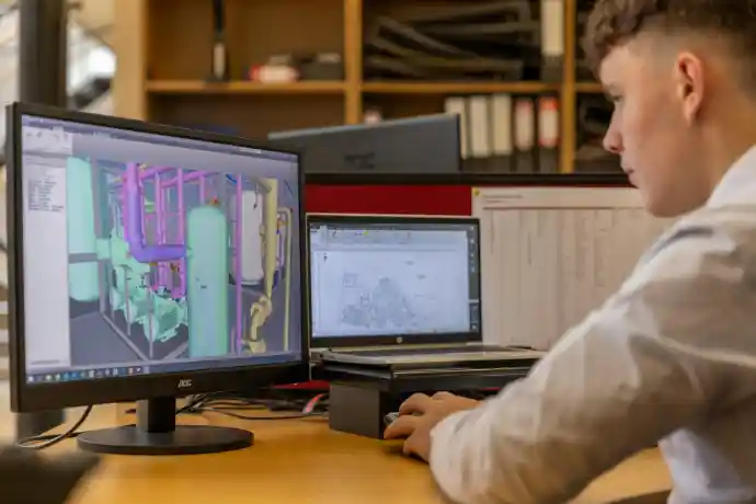 Engineer studying digital training materials on a screen in a modern workspace."